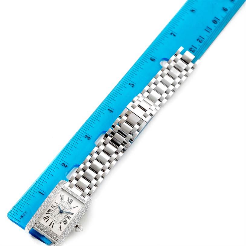 The image shows a top-down view of the Cartier Tank Americaine WB710001 Women
s White Gold Silver Dial WB710001 Women
s White Gold Silver Dial watch, including the face, bracelet, and a ruler for scale.