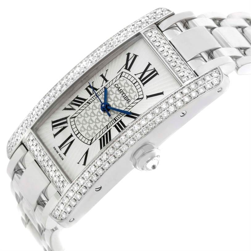 The image shows a Cartier Tank Américaine watch at an angle, highlighting its diamond-encrusted bezel, dial with Roman numerals, and metal bracelet.