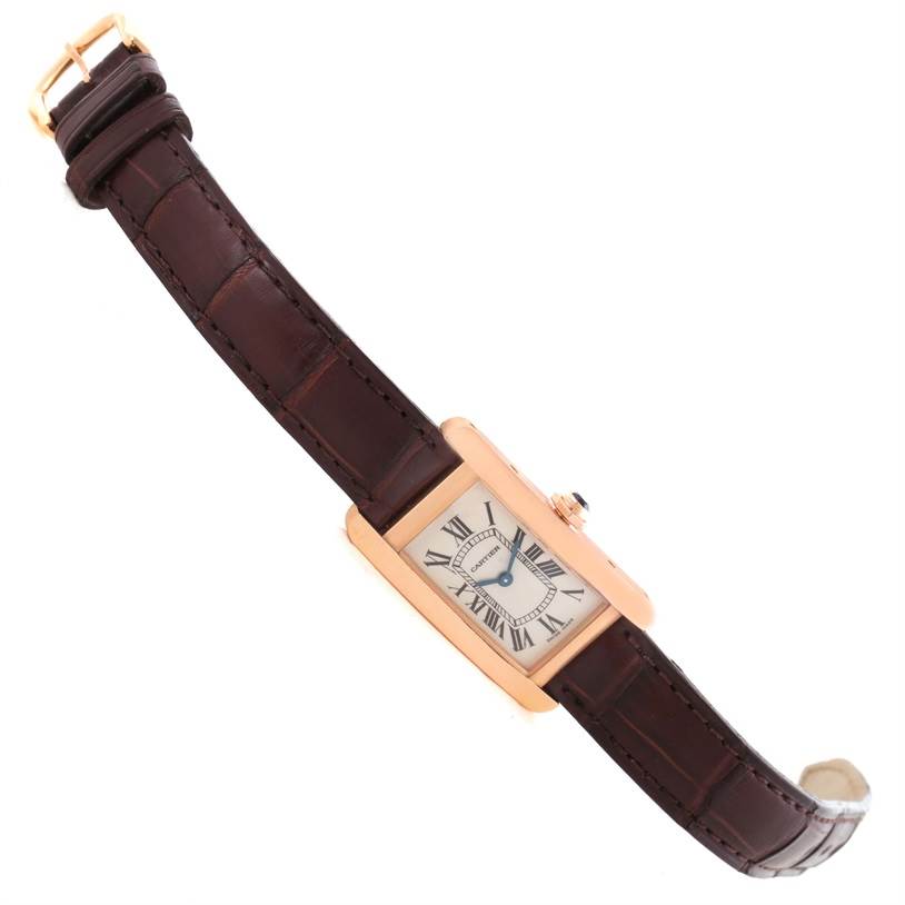 The image shows a Cartier Tank Américaine watch at a slight angle, highlighting the rectangular face, Roman numerals, and brown leather strap.