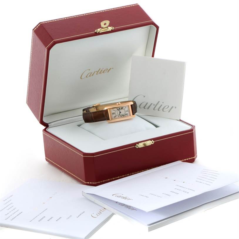 The Tank Americaine by Cartier is shown from the front, inside its red box, accompanied by booklets and paperwork.