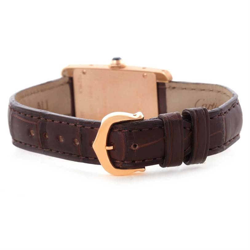 The image shows the back view of a Cartier Tank Américaine watch, highlighting its brown leather strap and gold buckle.