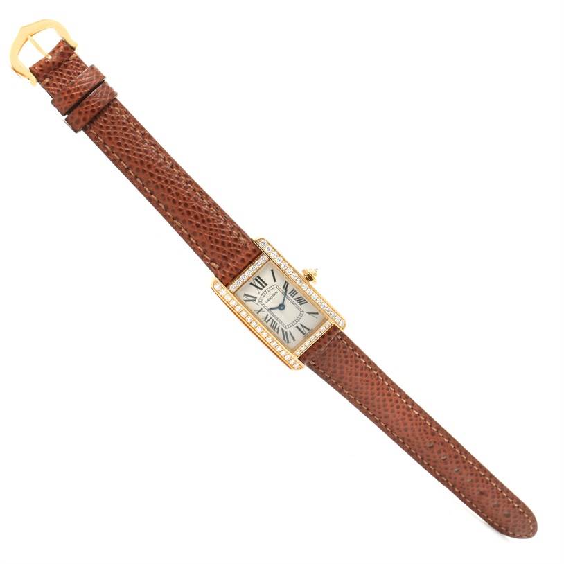 The image shows a top-down view of a Cartier Tank Americaine WB707231 Women
s Yellow Gold Silver Dial WB707231 Women
s Yellow Gold Silver Dial watch with a brown leather strap and rectangular face.