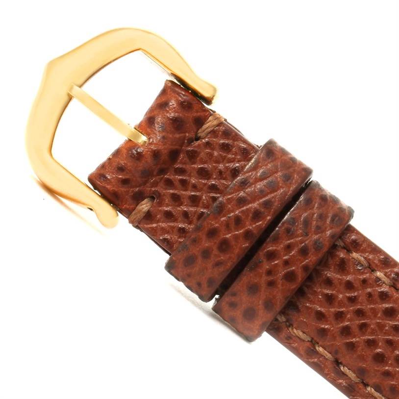 The image shows an angled view of the brown leather strap and gold buckle of the Cartier Tank Américaine watch.