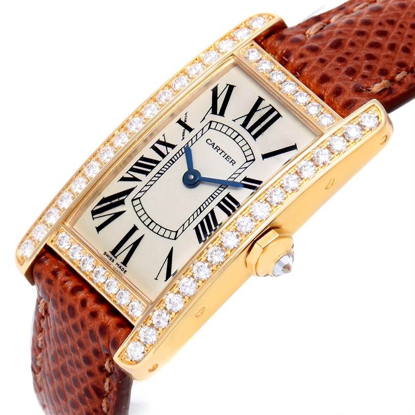 This image shows a close-up angle of a Cartier Tank Americaine WB707231 Women
s Yellow Gold Silver Dial WB707231 Women
s Yellow Gold Silver Dial watch with diamonds on the bezel and a brown leather strap.