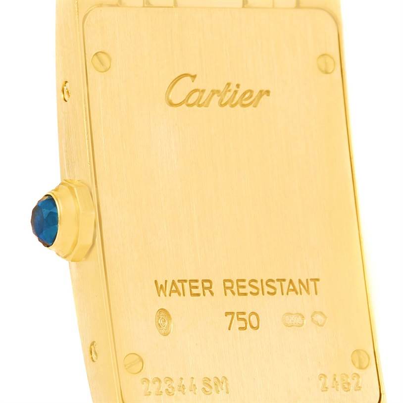This image shows the back of a Tank Americaine model watch by Cartier, highlighting the water resistance marking and crown with a blue stone.