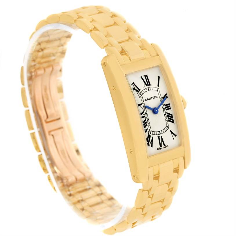 The image shows a Cartier Tank Americaine W26015K2 Women's Yellow Gold Silver Dial W26015K2 Women's Yellow Gold Silver Dial watch angled to display the face and gold bracelet band.