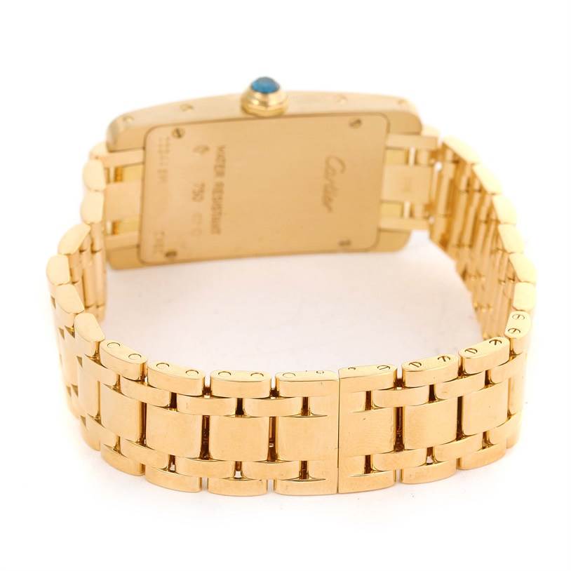 The image shows the back of a gold Cartier Tank Americaine W26015K2 Women's Yellow Gold Silver Dial W26015K2 Women's Yellow Gold Silver Dial watch, highlighting its case back and metal bracelet.