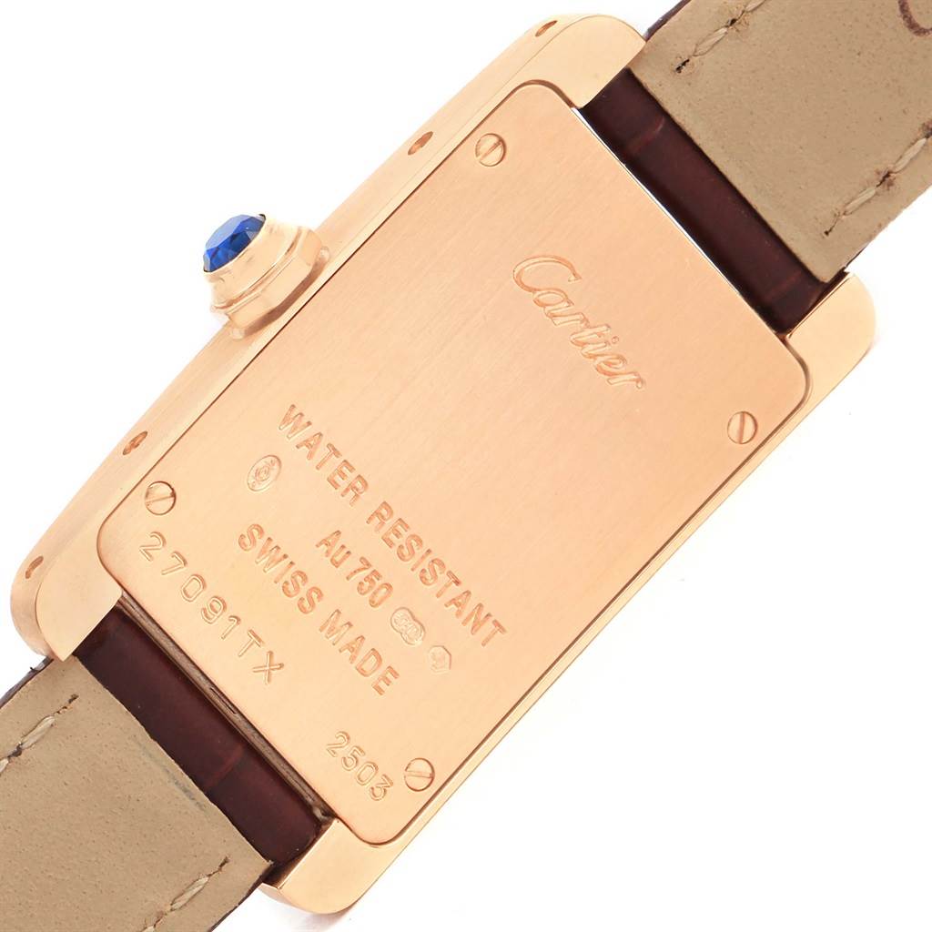 The image shows the back case of a Cartier Tank Americaine W2607456 Women
s Rose Gold Silver Dial W2607456 Women
s Rose Gold Silver Dial watch, displaying inscriptions and part of the strap.