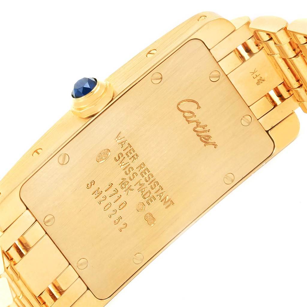 This image shows the back case and part of the band of a Cartier Tank Americaine W26015K2 Women
s Yellow Gold Silver Dial W26015K2 Women
s Yellow Gold Silver Dial watch, highlighting the engravings and details.