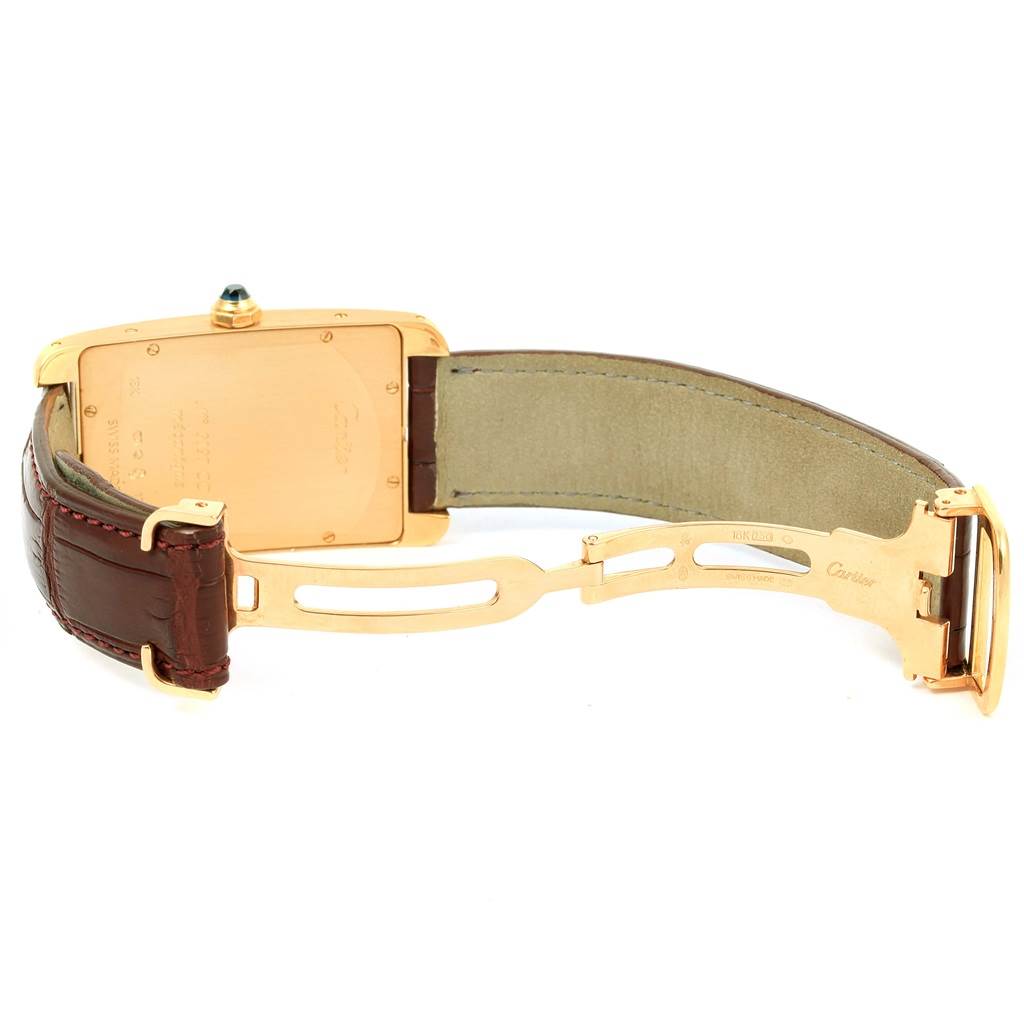 This image displays the backside and the clasp of the Cartier Tank Americaine 1735 Men
s Yellow Gold Silver Dial 1735 Men
s Yellow Gold Silver Dial watch, highlighting the leather strap and deployment buckle.