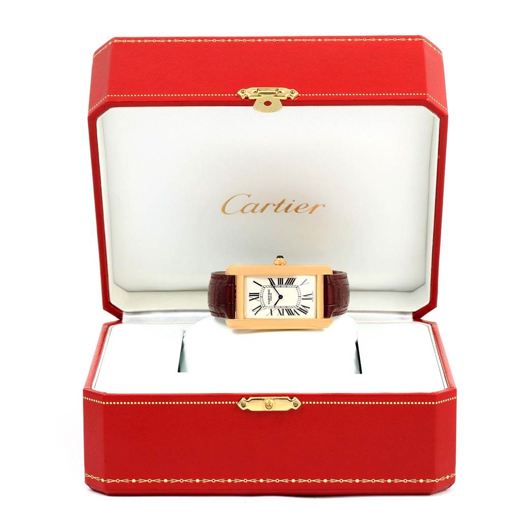 The Tank Americaine model by Cartier is displayed in an open red box, showing its rectangular dial and leather strap.