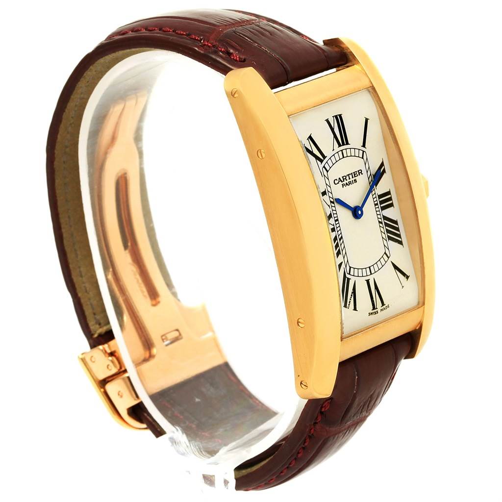 The image shows a side angle of the Cartier Tank Americaine 1735 Men
s Yellow Gold Silver Dial 1735 Men
s Yellow Gold Silver Dial watch, highlighting its rectangular case, Roman numeral dial, and leather strap.