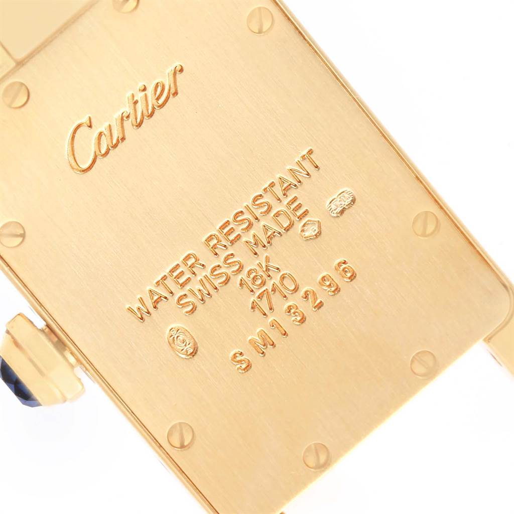 This image shows the case back of a Cartier Tank Americaine W26015K2 Women's Yellow Gold Silver Dial W26015K2 Women's Yellow Gold Silver Dial watch, highlighting its engravings and gold material.