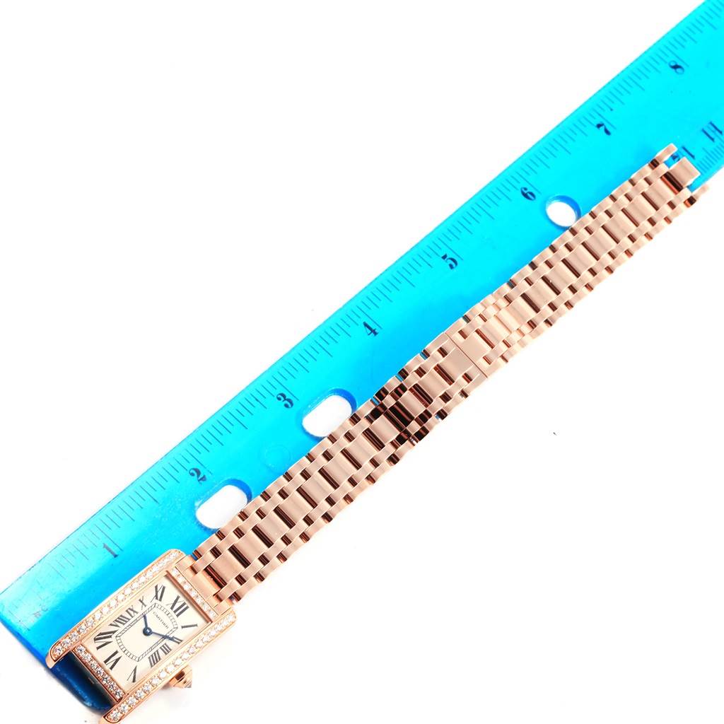 The image shows a Cartier Tank Americaine WB7079M5 Women's Rose Gold Silver Dial WB7079M5 Women's Rose Gold Silver Dial watch laid flat next to a blue ruler for measurement.