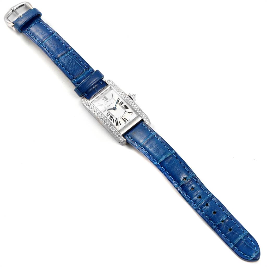 The image shows a top-down view of a Tank Americaine model watch by Cartier with a blue strap and diamond-studded rectangular face.