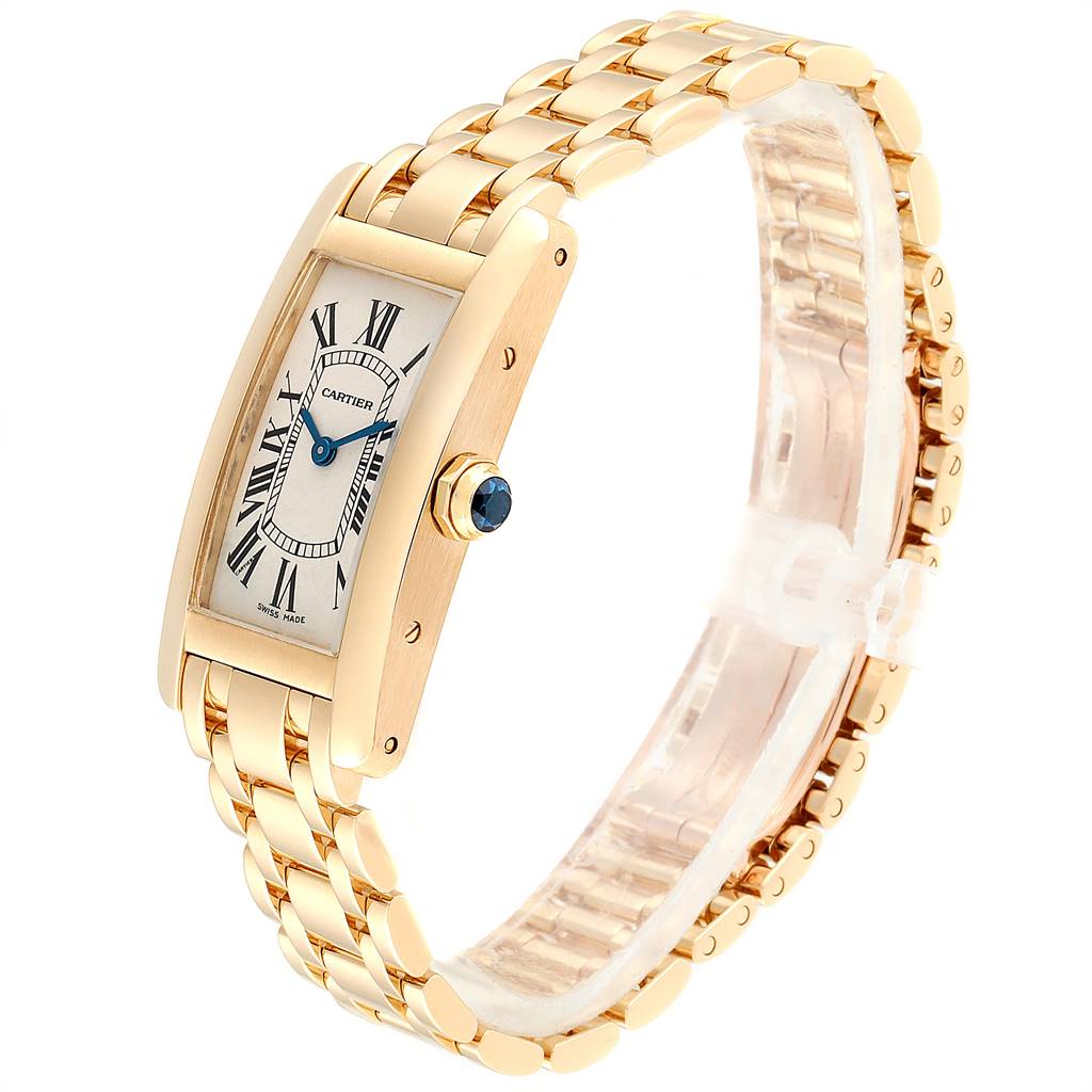 The image shows a Cartier Tank Americaine W26015K2 Women's Yellow Gold Silver Dial W26015K2 Women's Yellow Gold Silver Dial watch at a slight side angle, highlighting the gold case, bracelet, and crown with a blue gem.