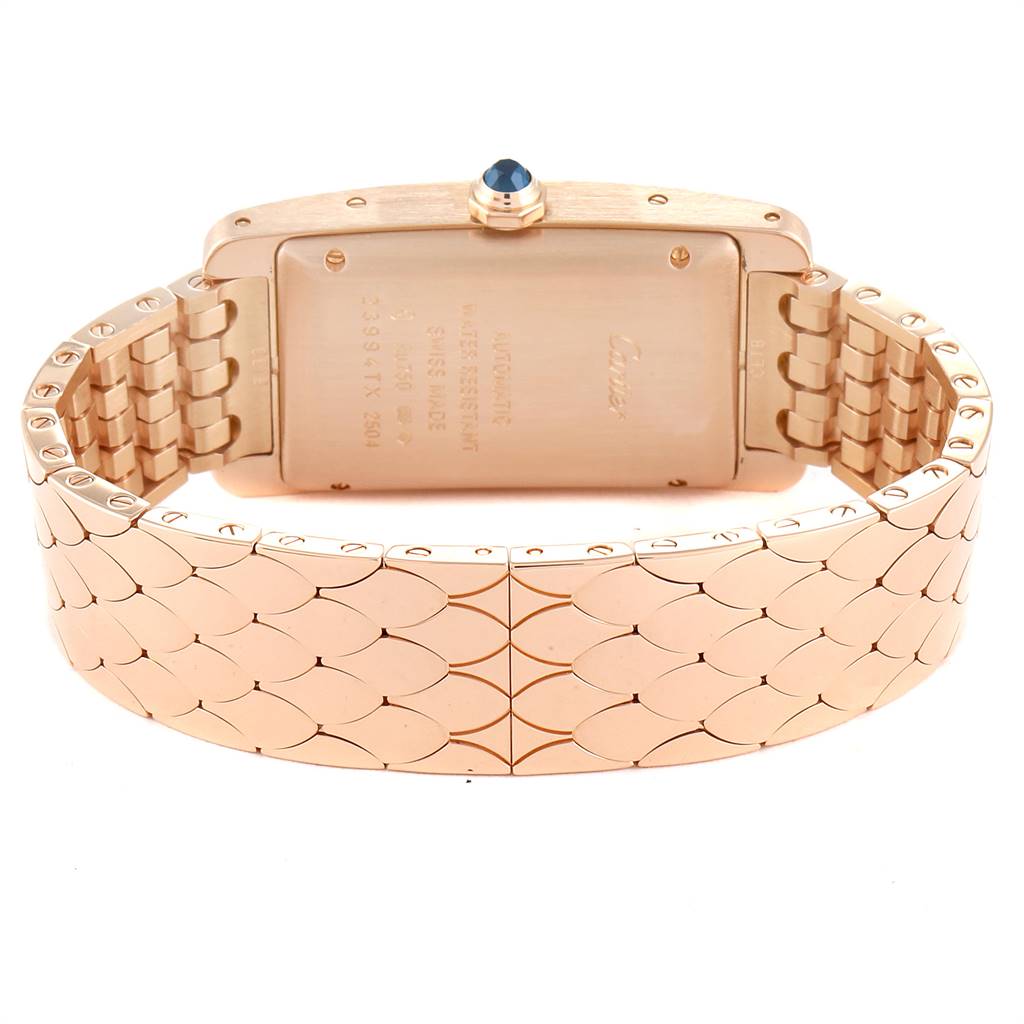 The image shows the back casing and bracelet of a Cartier Tank Américaine watch, featuring a gold-tone design with a blue cabochon crown.