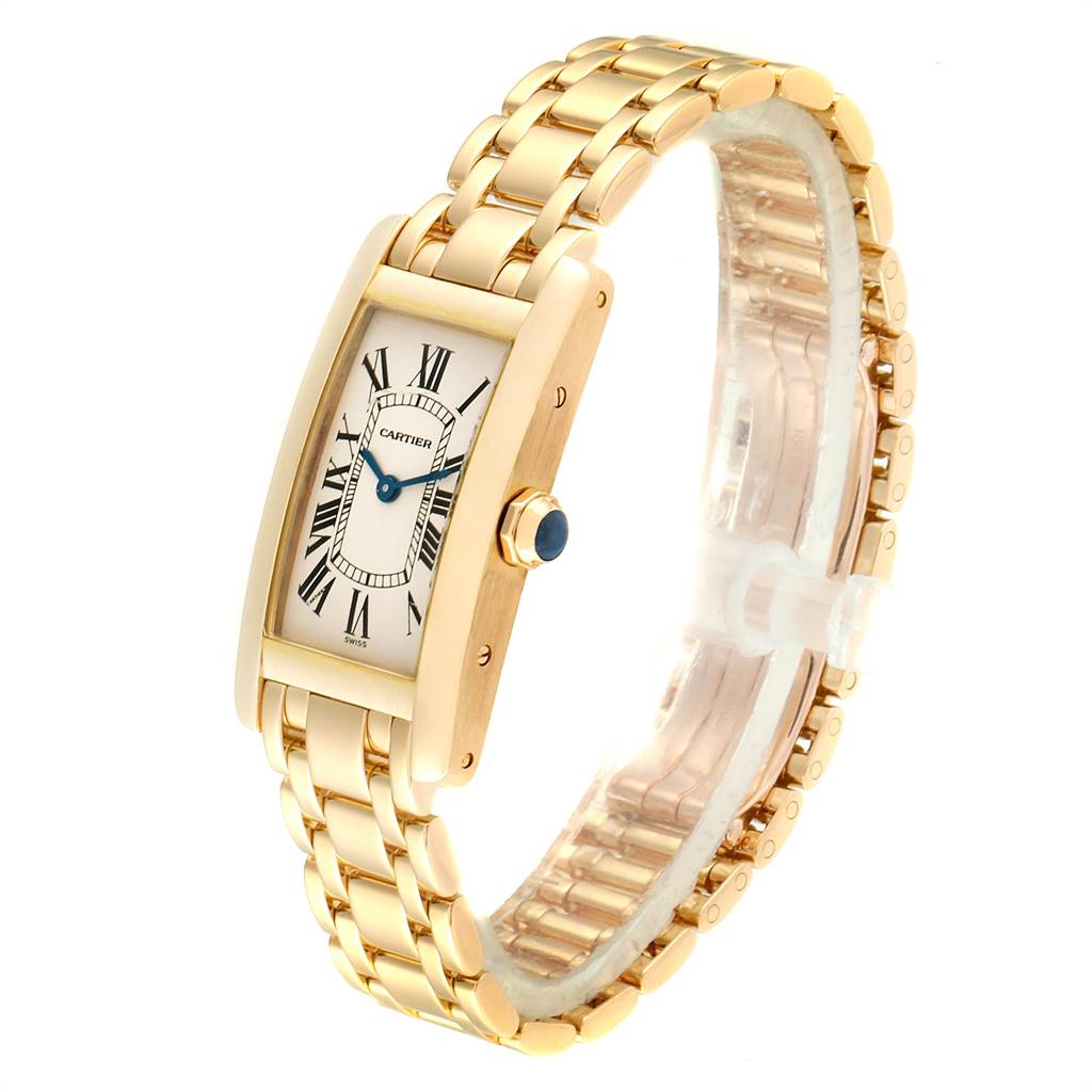 The Cartier Tank Americaine W26015K2 Women
s Yellow Gold Silver Dial W26015K2 Women
s Yellow Gold Silver Dial watch is shown at an oblique angle, displaying its gold case, white dial with Roman numerals, and gold bracelet.