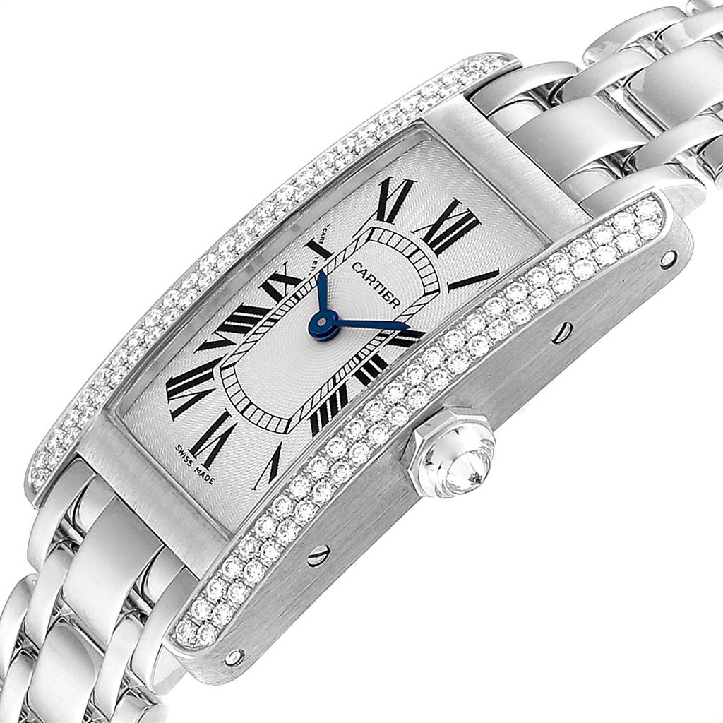 The image shows a Cartier Tank Americaine WB7018L1 Women
s White Gold Silver Dial WB7018L1 Women
s White Gold Silver Dial watch at an angle highlighting its diamond-set bezel, white dial, blue hands, and linked metal strap.