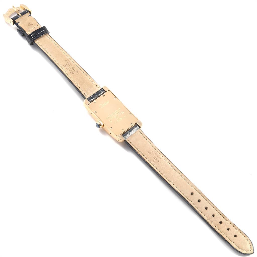 This image shows the back of a Cartier Tank Americaine W2601556 Women's Yellow Gold Silver Dial W2601556 Women's Yellow Gold Silver Dial watch laid flat, displaying the strap and case back.