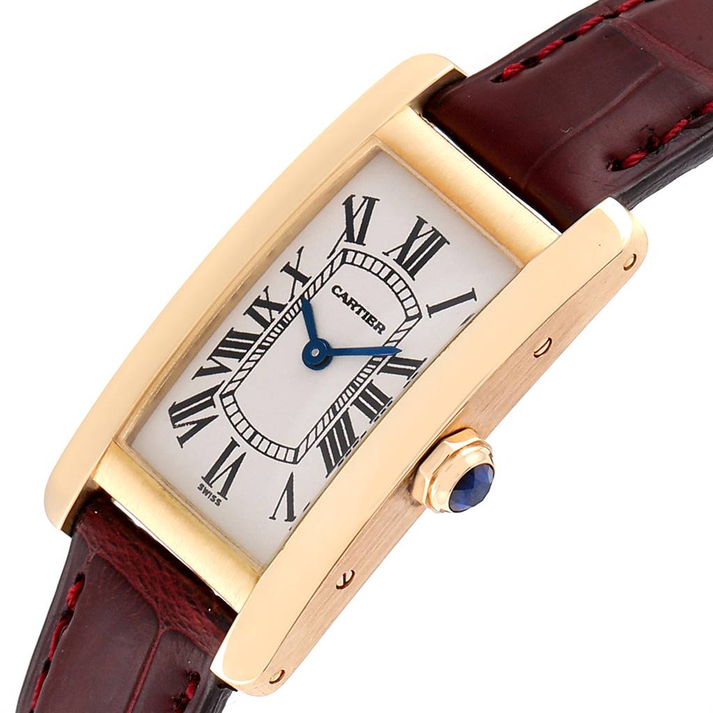 The Cartier Tank Americaine W2601556 Women's Yellow Gold Silver Dial W2601556 Women's Yellow Gold Silver Dial watch is shown at a slight angle, highlighting the face, Roman numerals, blue hands, and part of the leather strap.