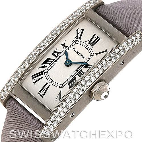 The image shows a close-up view of the Cartier Tank Americaine Women
s White Gold Silver Dial Women
s White Gold Silver Dial watch, highlighting its face, diamond bezel, and crown.