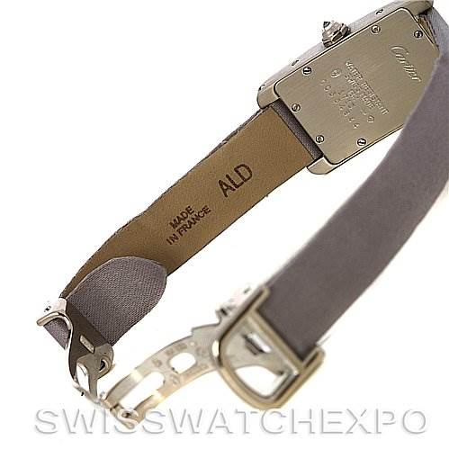 The image shows the back of the Tank Americaine model by Cartier, highlighting the case back and part of the leather strap with the clasp open.