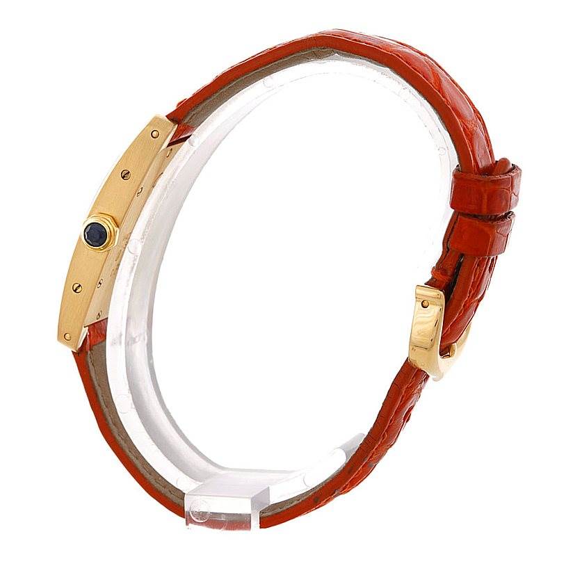 The image shows a side view of the Cartier Tank Americaine W2601956 Women's Yellow Gold Silver Dial W2601956 Women's Yellow Gold Silver Dial watch, highlighting its gold case, crown, and red leather strap with buckle.