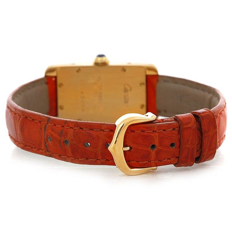 The image shows the back view of a Cartier Tank Americaine W2601956 Women's Yellow Gold Silver Dial W2601956 Women's Yellow Gold Silver Dial watch, highlighting its gold case and orange leather strap with a buckle.