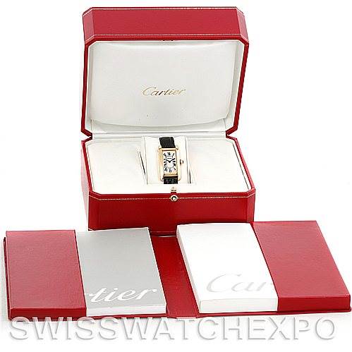 This image shows a Cartier Tank Américaine watch in its red presentation box with additional packaging and booklets.