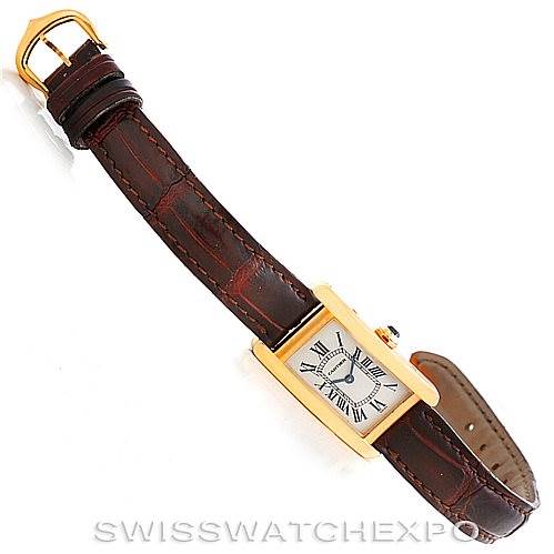 The Cartier Tank Américaine watch is shown from a top-down angle, displaying its face, strap, and buckle.