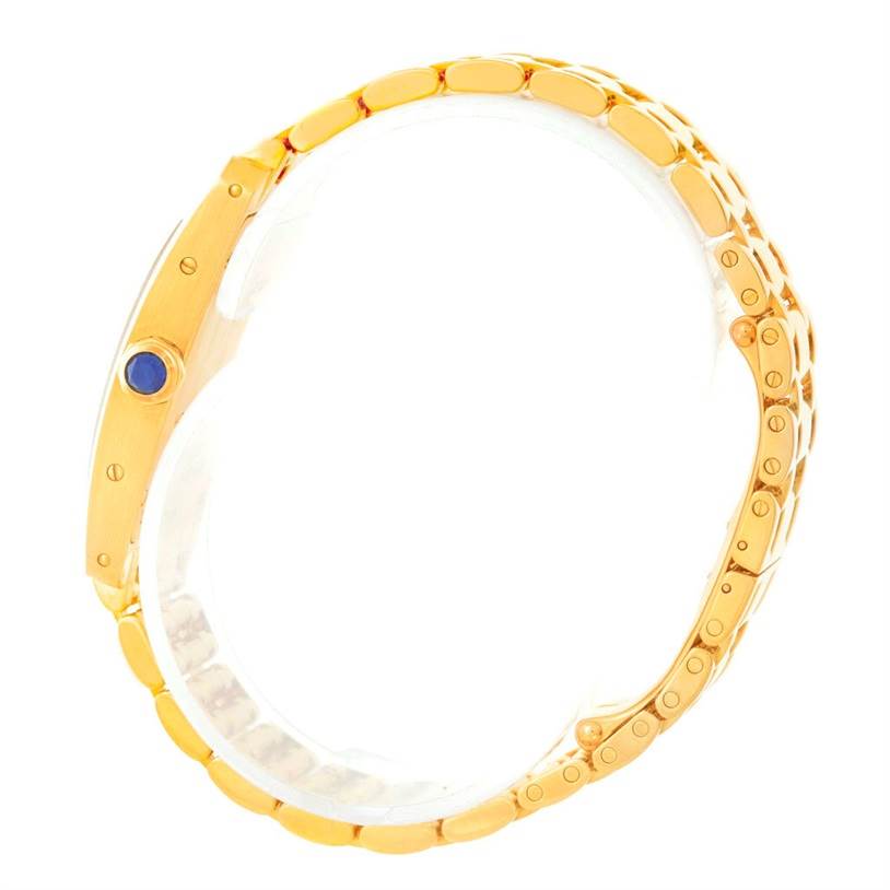 This image shows a side view of the Cartier Tank Americaine W26015K2 Women
s Yellow Gold Silver Dial W26015K2 Women
s Yellow Gold Silver Dial watch, highlighting its gold bracelet and blue cabochon crown.