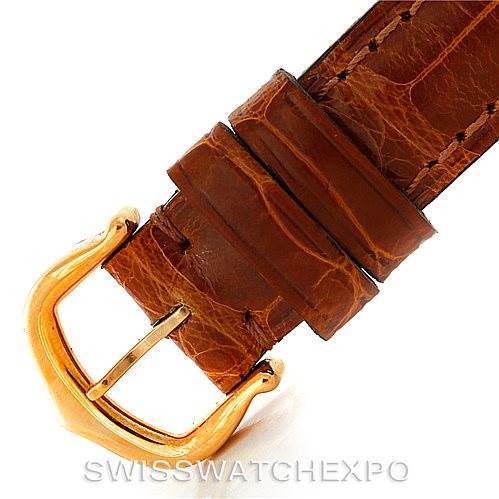 This image shows a close-up of the brown leather strap and gold buckle of a Cartier Tank Americaine W2601956 Women's Yellow Gold Silver Dial W2601956 Women's Yellow Gold Silver Dial watch.