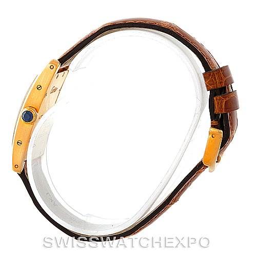 The image shows the side view of the Cartier Tank Americaine W2601956 Women's Yellow Gold Silver Dial W2601956 Women's Yellow Gold Silver Dial watch, highlighting the gold case, blue cabochon crown, and leather strap.