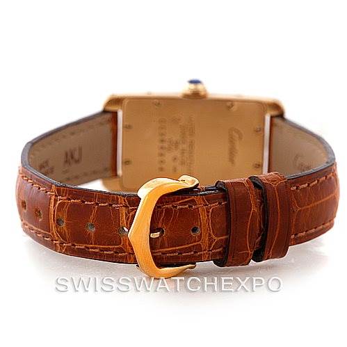The image shows the back view of a Cartier Tank Américaine watch, highlighting its brown leather strap and gold buckle.
