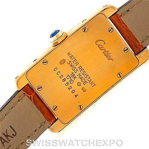 The image shows the back of the Tank Americaine watch by Cartier, highlighting its gold case, screws, and leather strap.
