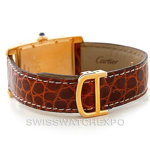 The image shows the back of a Cartier Tank Américaine watch and its brown leather strap with a gold buckle.