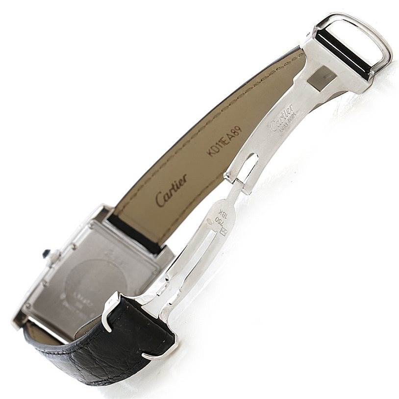 This image shows the underside of a Cartier Tank Americaine Women
s White Gold Silver Dial Women
s White Gold Silver Dial watch, highlighting its leather strap and deployment clasp.