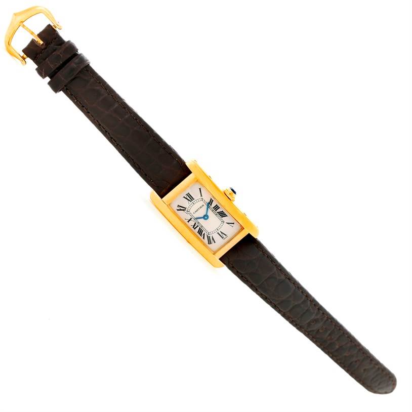 The image shows a Cartier Tank Americaine W2601956 Women's Yellow Gold Silver Dial W2601956 Women's Yellow Gold Silver Dial watch with a gold case and brown leather strap laid flat, viewed from an angled top-down perspective.