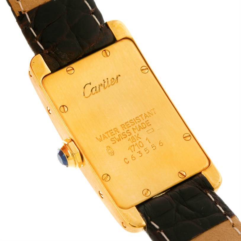 The image shows the back case of the Cartier Tank Américaine watch, highlighting the 18K gold, water resistance, and serial number details.