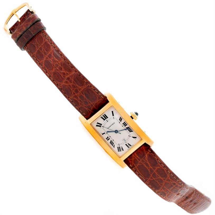 The image shows a Cartier Tank Americaine Women's Yellow Gold Silver Dial Women's Yellow Gold Silver Dial watch with a brown leather strap from an angled top-down view.