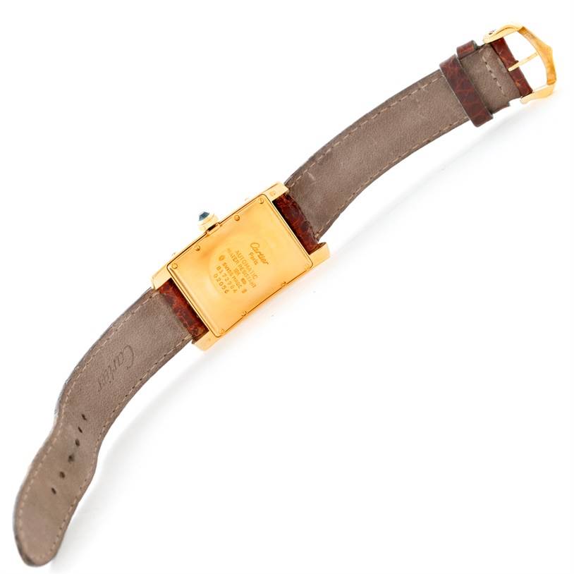 The image shows the back of a Tank Américaine Cartier watch, displaying the case back, crown, and straps.