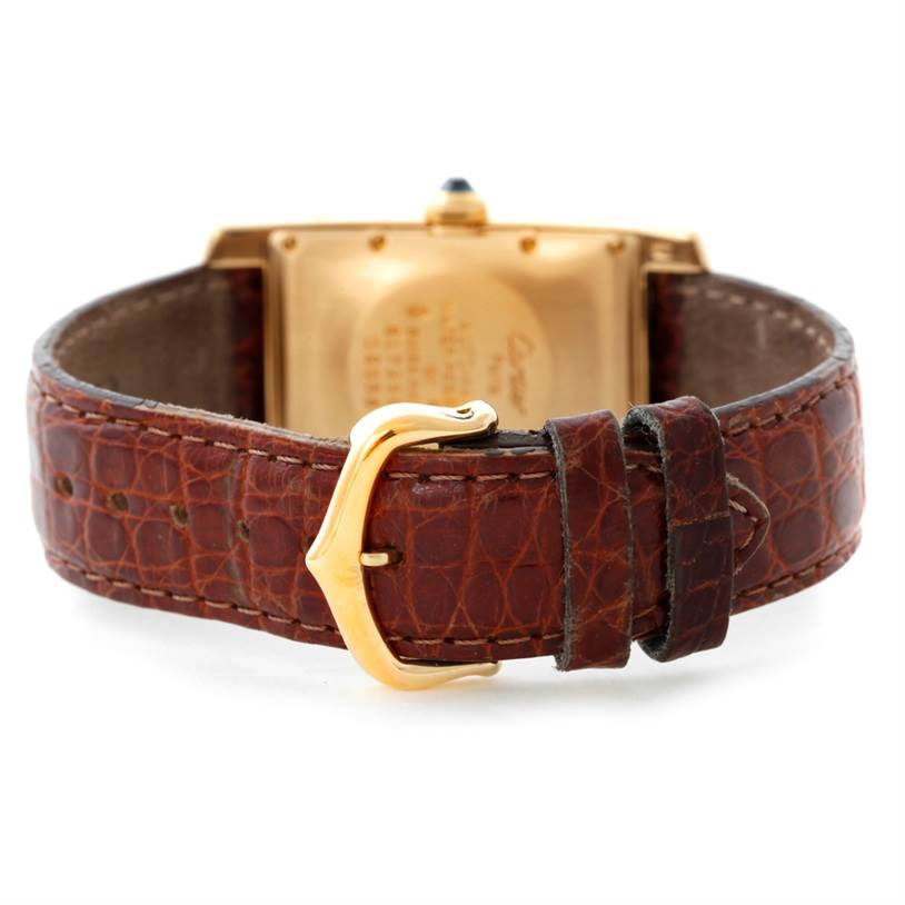 This image shows the back of the Cartier Tank Americaine Women's Yellow Gold Silver Dial Women's Yellow Gold Silver Dial watch with a focus on the brown leather strap and gold-colored buckle.