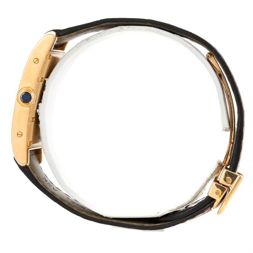 This is a side view of the Cartier Tank Americaine W2600351 Yellow Gold Silver Dial W2600351 Yellow Gold Silver Dial watch, showing the crown, case, and leather strap.