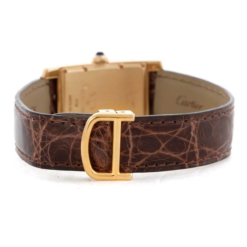 The image shows the back angle of a Cartier Tank Americaine W2600351 Yellow Gold Silver Dial W2600351 Yellow Gold Silver Dial watch, highlighting the brown leather strap and gold buckle.
