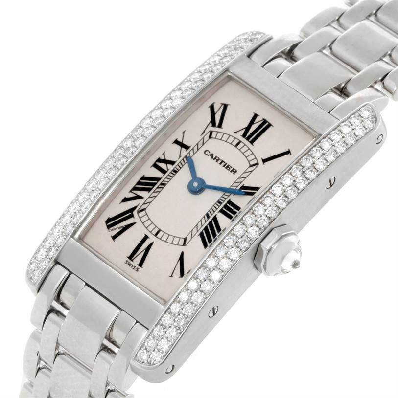 The image shows a Tank Americaine watch by Cartier at an oblique angle, displaying the face, crown, and part of the bracelet.