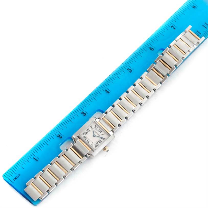 The Cartier Tank Française watch is shown from a top-down angle, next to a blue ruler indicating its length.