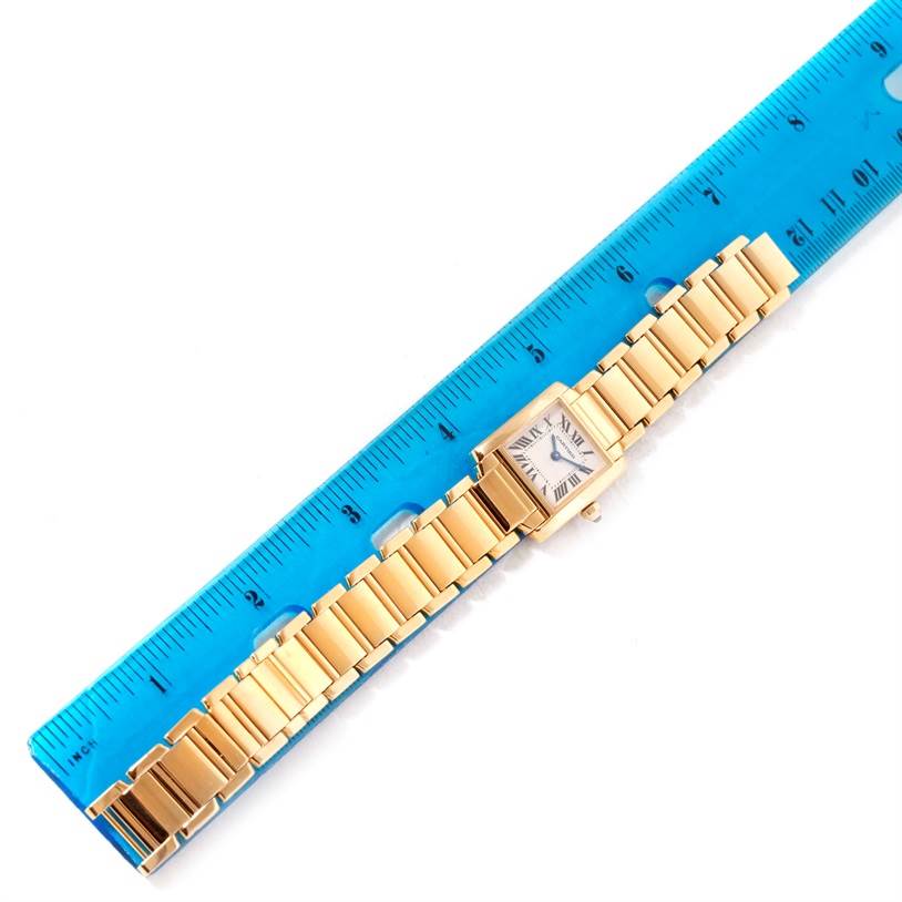 This image shows a full view of a Tank Francaise model watch by Cartier, positioned next to a ruler for size reference.