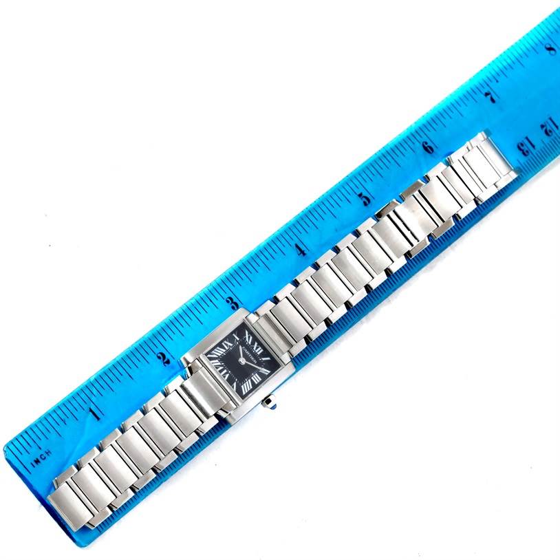 The Cartier Tank Française watch is shown from a top-down view, displaying its bracelet and face placed against a blue ruler for scale.
