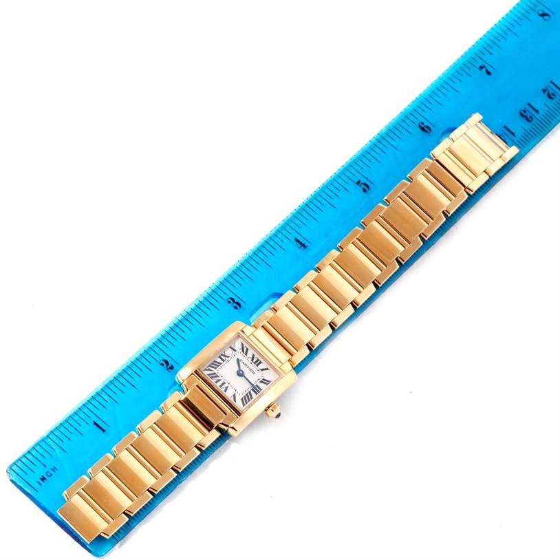 The image shows a Cartier Tank Francaise W50002N2 Women's Yellow Gold Silver Dial W50002N2 Women's Yellow Gold Silver Dial watch laid next to a blue ruler for size reference.